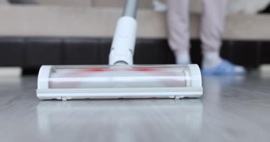 Hizmetçi, kablosuz elektrik süpürgesiyle yerleri temizliyor. Temizlik hizmetleri kavramı