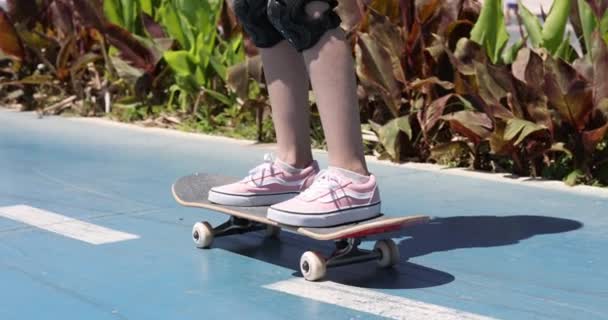 女の子の子供は晴れた日に通りをスケートボードに乗っています スケートボードのコンセプトを学ぶ — ストック動画