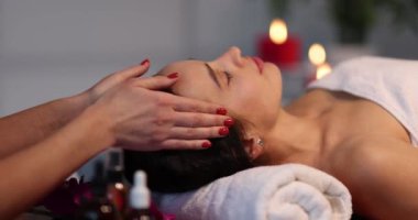 Güzellik uzmanı spa merkezinde müşterinin yüzüne masaj yapıyor. Yüz bakımı ve yaşlanma karşıtı tedavi kavramı