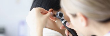 Kulağı otoskopla inceleyen kadın otolarolog. Doktor randevusunda kulak ağrısı olan hasta. Otolaryngology, tıp ve sağlık konsepti