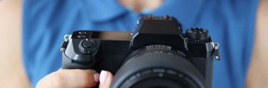 Fotoğraf stüdyosunda elinde kamera olan mavi elbiseli kadın fotoğrafçı. Profesyonel sanatçı yeni fotoğraf makinesi modelini elinde tutuyor. Yaratıcı kavram