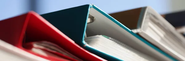 Close-up of stack of colourful folders for documents on table. Pile of papers. Paperwork idea. Blockage at work concept. Business papers for annual reports files