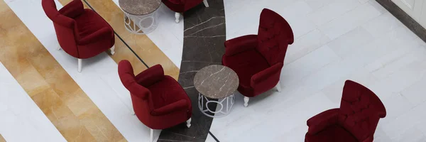 Top view of stylish arm-chairs and tables in hall or hotel lobby. Fashionable restaurant or cafe. Stylish hall interior. Tourism and travelling concept