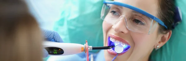 口腔科诊所女性病人的肖像用特殊的设备美白牙齿 患者戴防护眼镜 Teethcare Concept — 图库照片