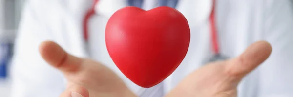 医療従事者のクローズアップは 赤いプラスチック製の心臓を投げ 手のひらでそれをキャッチします 寄付や慈善団体を通して命を救う 心臓病 医療の概念 — ストック写真