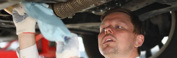 Man repairman repairing car under hood at service station. Professional and high quality auto repair concept