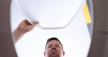 Adamın biri tuvaletten akıllı telefonu çıkardı. Düşük açılı bir atış. Bir erkeğin yüzünde tiksinti ve sıkıntı