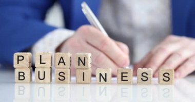 Bir işadamı, ön plandaki tahta küplere yazı yazdığını yazıyor. Sunum ve teklif