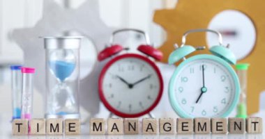 Alarm saatlerinin arka planına karşı tahta küplerin üzerindeki yazıt zaman yönetimi, yakın plan. Verimliliği artırma kavramı