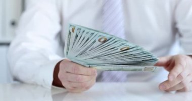 İş adamı bir deste dolar gösteriyor, yakın çekim, yavaş çekim. İş yatırımı, kredi, tutucu