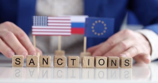Stole Jsou Dřevěné Kostky Nápis Sankce Pozadí Politik Vlajkami Zpomalení — Stock video