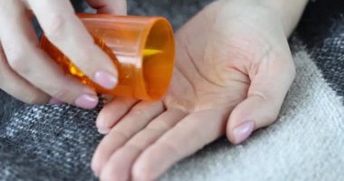 Bir kadın kavanozdan sarı kapsüller dolduruyor, elleri yakın çekim. Gıda takviyeleri, omega 3, sağlık desteği