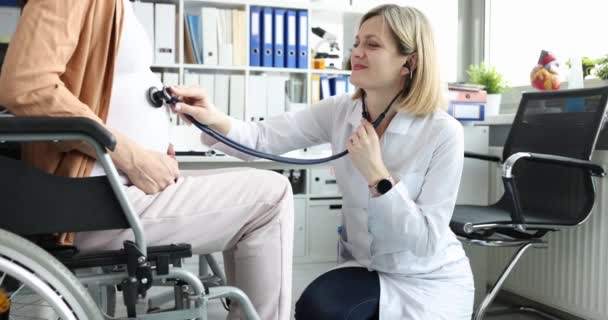 医者は車椅子の妊婦の腹に聴診器で耳を傾け ゆっくりと動きます 障害と母親 — ストック動画