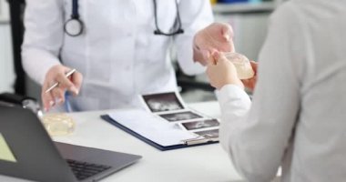 Bir doktor bir kadına silikon göğüs implantı gösterir, yakın çekim, yavaş çekim. Estetik ameliyat, göğüs kanseri.