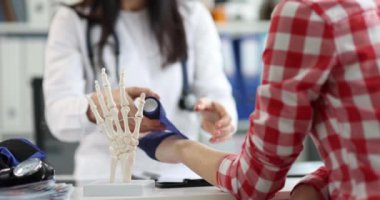Doktor, kadının bileğine elastik bant takar. Yakın çekim, ağır çekim. Burkulma için bandaj, travma.