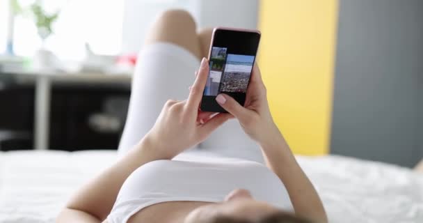 Kadın Yatakta Uzanıyor Dinlenme Telefonundaki Fotoğraflara Bakıyor Uykusuzluk Seyahat Konseptinden — Stok video