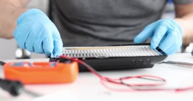 Elektrikçi masadaki aydınlatma ekipmanlarını tamir ediyor. Teknisyen eski lambaların çalışmasını denetliyor