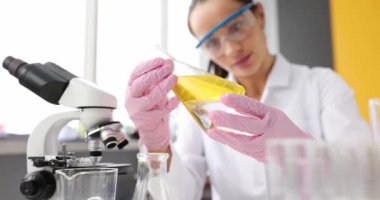 Koruyucu gözlüklü doktor laboratuarda sarı bir sıvıyla test tüpü tutuyor. Laboratuvar teşhisi yağ araştırma konsepti
