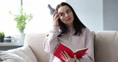 Düşünceli üzgün kadın kanepede oturarak günlük tutuyor. Günlük konseptinde duygu günlüğü ve depresif notlar