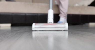 Kadın kablosuz elektrik süpürgesini kaplamaları temizlemek için kullanıyor. Temizlik hizmetleri kavramı