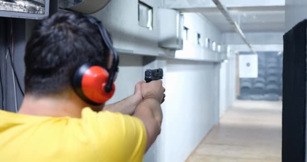 男性枪手手持手枪向目标射击的后视镜 武器训练射击场 — 图库视频影像