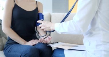 Doktor evde hastanın kan basıncını ölçer. Kalp hastalığında tansiyon kontrolü