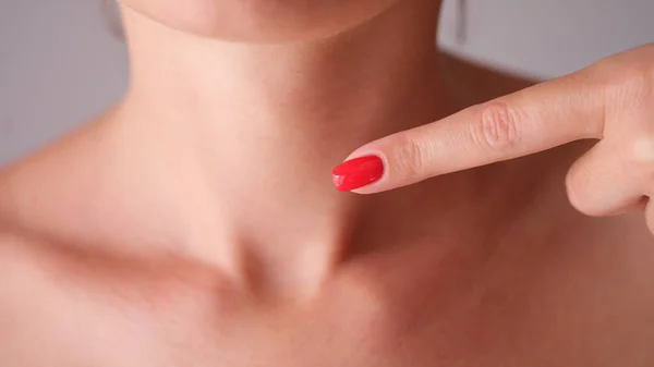 甲状腺が閉じて首の部分に指を指す赤いマニキュアを持つ女性 自己免疫性甲状腺炎の概念の診断と治療 — ストック写真