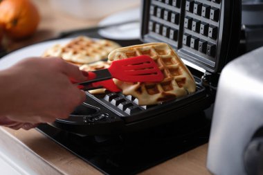 Evde waffle ızgarası üzerinde waffle hazırlayan biri var. Lezzetli waffle konsepti tarifi