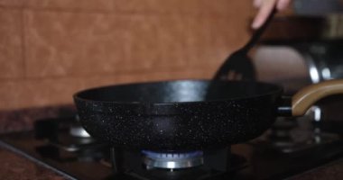 Kadın, kullanılmış sebze yağıyla kızartma tavasını kapatıyor. Kısa devre kavramında ürünleri kızartma