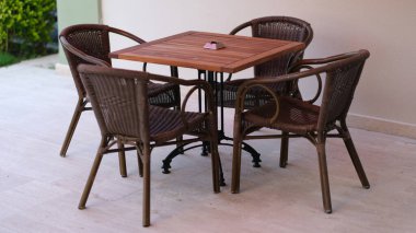 Yazlık ahşap masa ve verandada hasır sandalyeler. Yaz mobilya konsepti