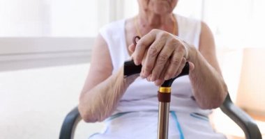 Yaşlı kadın elleri ahşap bastonun üzerinde yakın plan. Huzurevi ve yalnızlık kavramı