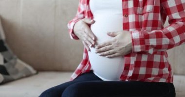 Hamile kadın göbeğine şefkatle dokunuyor. Çocuk konseptinin doğmasını beklemek