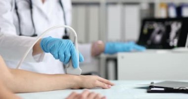 Doktor, klinikte hasta bileğinin ultrason muayenesini yürütüyor. El eklemleri kavramında ağrı