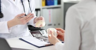 Doktor, klinikteki bir kadına silikon silikon implantlar gösteriyor. Estetik ameliyat ve göğüs gerdirme konsepti