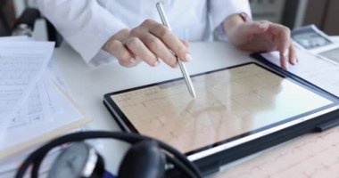 Doktor, klinikte elektrokardiyogramla tablet tutuyor. Kalp ritim bozukluğu ve kalp tedavisi konsepti.