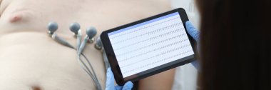 Doktor, klinikte dijital tablet kullanan hasta adama kardiyogram çekiyor. Acil kalp bakımı konsepti
