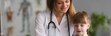 Pediyatrist kadın doktor muayenehanedeki kızla iletişim kuruyor. Çocuk konsepti için tıbbi sigorta