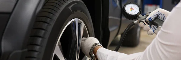 Technician checks tire pressure of car. Tire service concept