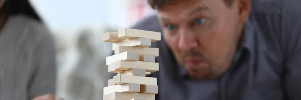男は木の長方形のブロックから背の高い塔を組み立てる ボードゲーム又はビジネスビルのコンセプト — ストック写真