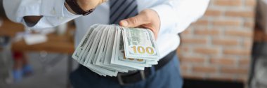 Erkek ellerinin yakın çekimi, bir sürü banknotla tamam işareti gösteriyor. Büyük borcu olan bir iş adamı, aylık maaş, yatırım için para. Finans, zenginlik, başarı, mali ilerleme, bankacılık kavramı