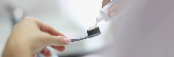 近距离人员在牙刷上涂牙膏 准备在浴室里清洁牙齿 准备好 早上例行公事 身体和面部护理的概念 模糊的背景 — 图库照片