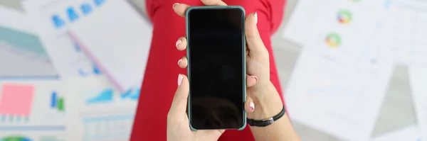 Top view of woman holding phone with black screen, turn off device, no connection, broken smartphone, mockup. Technology, work collapse, damage concept. Copy space. Blurred background