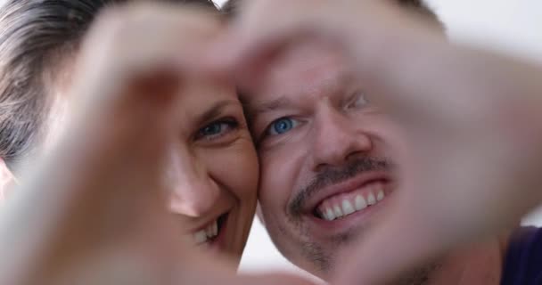 幸福的爱情夫妇肖像与手工制作的心形框架 恋爱中的男人和女人在一起摆出愉快的姿势 看着心形笑逐颜开 — 图库视频影像