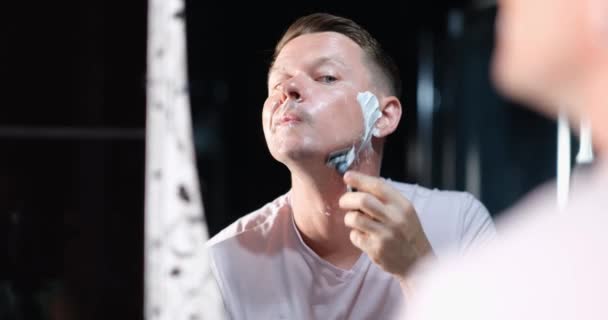 年轻英俊的男人在镜子前用泡沫剃须刀刮胡子 基本刮胡子技术概念 — 图库视频影像