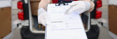 Üniformalı ve maskeli bir adamın portresi alıcıya imzalaması için teslim makbuzu verir. İşçi bilgi kağıdını doldurmak istiyor. Teslimat hizmeti kavramı