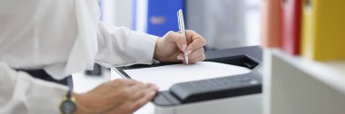 Yazıcı makinesindeki kadın sekreter ya da ofis çalışanı kağıtlarının yakın çekimleri. Takım elbiseli bir şirket çalışanı evrak dolduruyor. İş hayatı, iş kavramı.