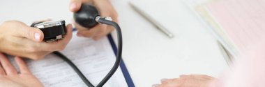 Doktorun hastaların tansiyonlarını tonometre cihazıyla ölçmesine yakın çekim. Aile doktoruna planlı check-up. Tıp, sağlık, yardım kavramı