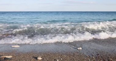 Kayalık sahilde dalgalar ve deniz sörfü. Yaz yolculuğu konsepti. Yaz günü sahilin manzarası.