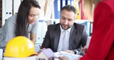 Mimarlar ve tasarımcılardan oluşan bir ekip planlarını planlarla birlikte masada tartışıyor. İnşaat takımı proje mimarı konsepti