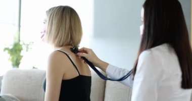 Professional pulmonologist examines young female patient with cough with stethoscope. Check your lungs for pneumonia.